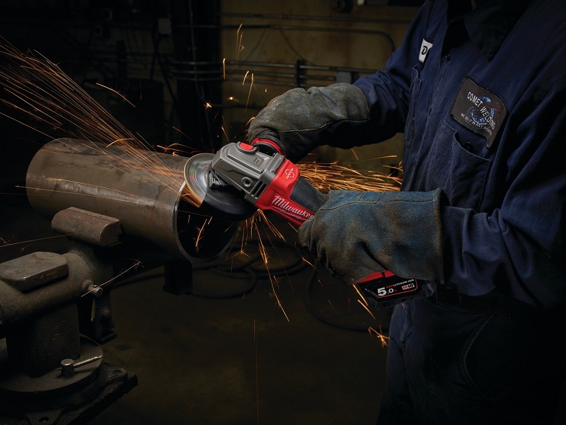 Worker works with cordless angle grinder