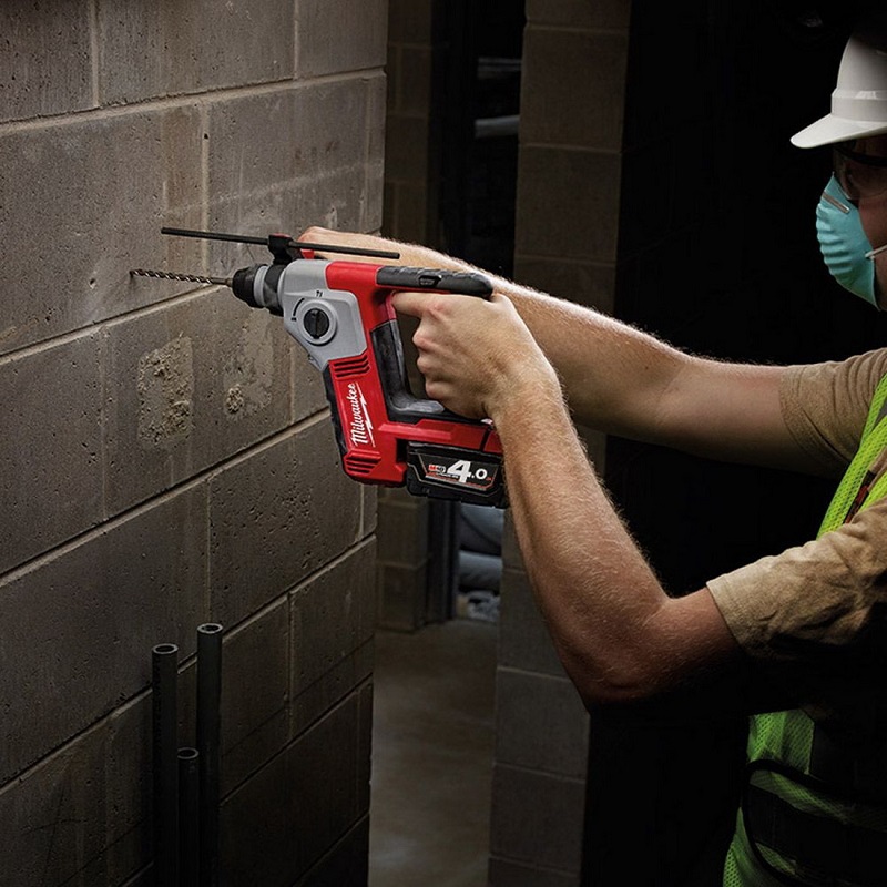 Worker works with rotary hammer drill