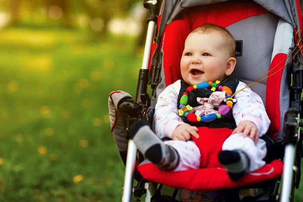 smiling baby in red stroller 
