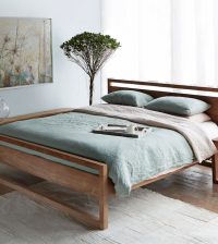bed with wooden teak frame and green sheets