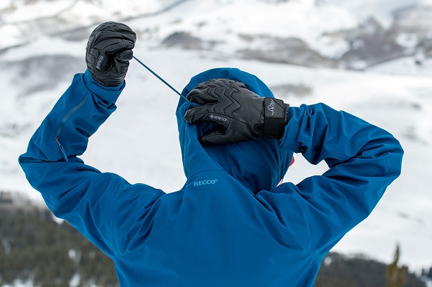 man putting his hood up with snowboard gloves on 