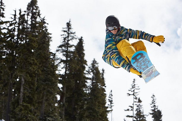 man dressed in full snowboard gear riding mid air 