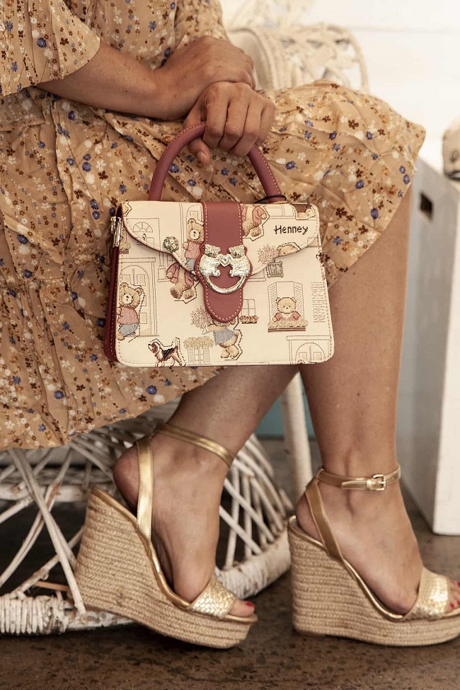 picture of a woman sitting on a chair wearing floral dress, purse with teddy bears and golden comfortable wedges