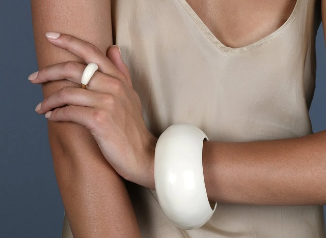 picture of a woman with hand crossed wearing nude dress and white resin luxury ring and resin bangle 