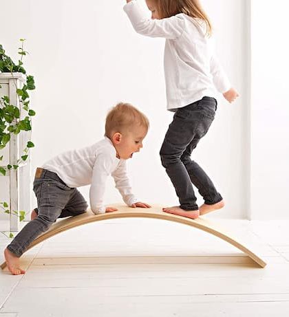Two kids playing on curved balance board