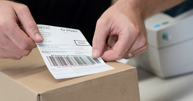 men putting shipping label on a box 