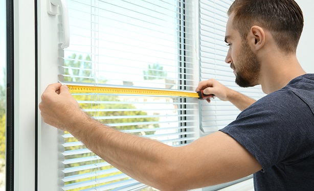 man measuring a window for curtains and blinds