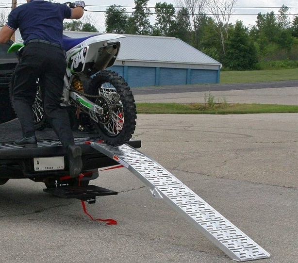 Man pushing motocross on ramp in truck