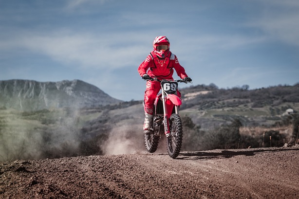 A guy driving a red motocross dirt bike on a track